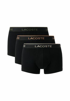 Drei Paar schwarze Lacoste Boxershorts mit gebrandetem Taillenbund in verschiedenen Farben, versetzt angeordnet.