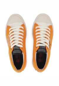 Narančaste platnene tenisice bijelih vezica i gumenih potplata. Na strani i unutarnjoj podlozi imaju crno-bijele tiskane uzorke.