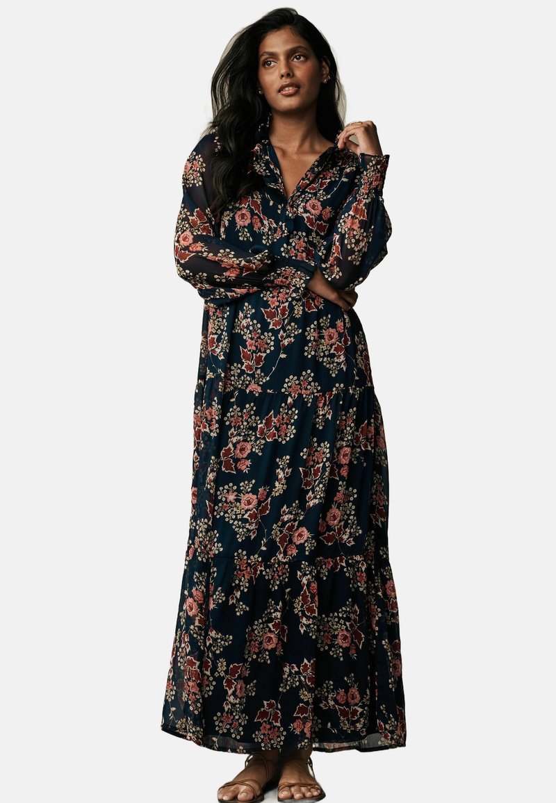 Maxi dress with a navy background, featuring floral patterns in shades of pink and green, long sleeves, and a tiered hem design.