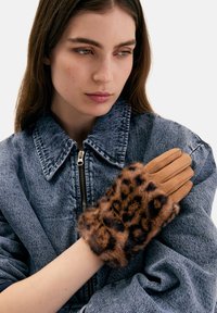 Gants couleur fauve avec un revers en fourrure à imprimé léopard, accompagnés d'une veste en denim gris texturé avec un grand col et une fermeture éclair.