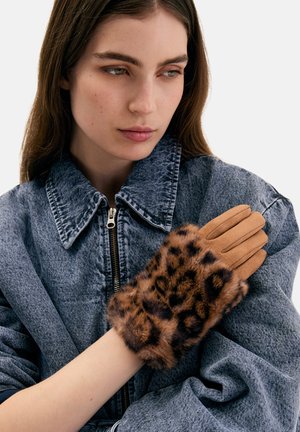 Guantes color beige con puño de piel estampada de leopardo, acompañados de una chaqueta vaquera gris texturizada con gran cuello y cierre de cremallera.