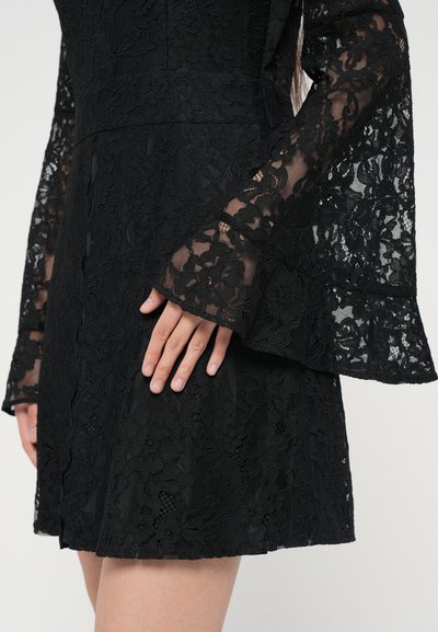 Black lace dress featuring long, flared sleeves, intricate floral patterns, a fitted bodice, and a short hemline. The fabric has a textured appearance.