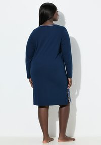 Abito a maniche lunghe color blu navy con scollo rotondo e spacchi laterali, presenta un motivo floreale colorato sull'orlo, realizzato in morbido tessuto jersey.