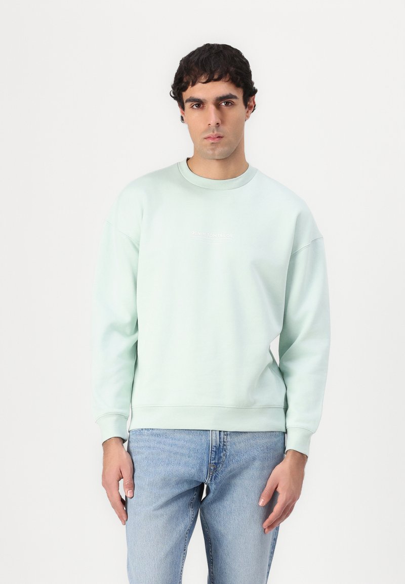 Lyse mintgrøn sweatshirt lavet af blødt stof, med rund hals og ribbede ærmer. Forsiden har et diskret hvidt logo.