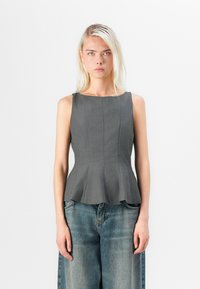 Grå ärmlös peplumtop med en strukturerad passform, med vertikal sömnad och en slät yta, i kombination med avslappnade blå denimbyxor.