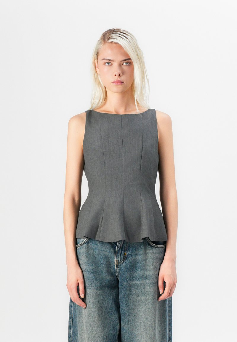 Grå ärmlös peplumtop med en strukturerad passform, med vertikal sömnad och en slät yta, i kombination med avslappnade blå denimbyxor.