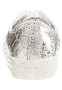 Metallisch silberner Sneaker mit einer strukturierten, reptilienähnlichen Oberfläche und einer weißen Gummisohle. Verfügt über genähte Akzente und ein auffälliges Logo an der Ferse.