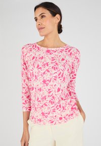Maglia a maniche lunghe realizzata in tessuto morbido, con un audace motivo floreale rosa su uno sfondo chiaro, scollo rotondo e vestibilità comoda.