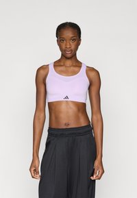 Ανοιχτό μωβ αθλητικό μπουστάκι με υφή και φαρδιές τιράντες, με κεντρικό μαύρο λογότυπο, σε συνδυασμό με μαύρο φαρδύ παντελόνι.