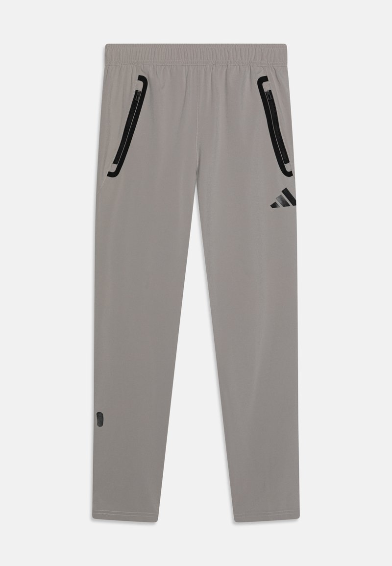 Šedé športové nohavice vyrobené z ľahkého materiálu, s čiernymi zipsovými vreckami a logom Adidas na hornej ľavej stehno.