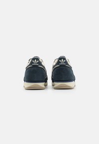 Marine sportieve schoenen van suede materiaal, crèmekleurige accenten, textuur mesh panelen en een reliëf logo op de hiel. Rubberen buitenzool voor grip.