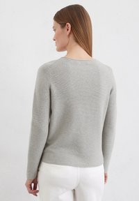 Grijze gebreide trui met lange mouwen en een ronde halslijn. Heeft een gladde textuur en een licht getailleerde silhouet.