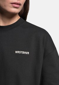 Černá bavlněná mikina se zaobleným výstřihem a krátkými rukávy. Obsahuje vyšívaný nápis "WRSTBHVR" v kontrastní bílé barvě.