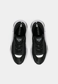 Schwarze Sneakers mit einem glatten Obermaterial und Mesh-Akzenten, weißem Logo und einer dicken weißen Sohle. Enthält schwarze Schnürsenkel und gestreifte Details.