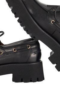 Black leather shoes with a chunky, textured sole, featuring gold accents and a lace-up design. Smooth finish highlights craftsmanship.