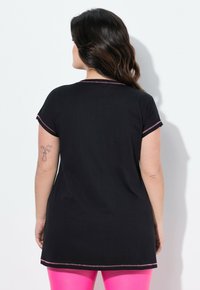 Túnica negra de mangas cortas, con un cuello redondo y detalles de costura en rosa. La tela parece suave y lisa al tacto.