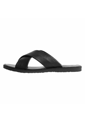 Sandales à glissière en cuir noir avec une conception de bride épaisse en croix, semelle plate et texture lisse. Semelle extérieure en caoutchouc antidérapante.