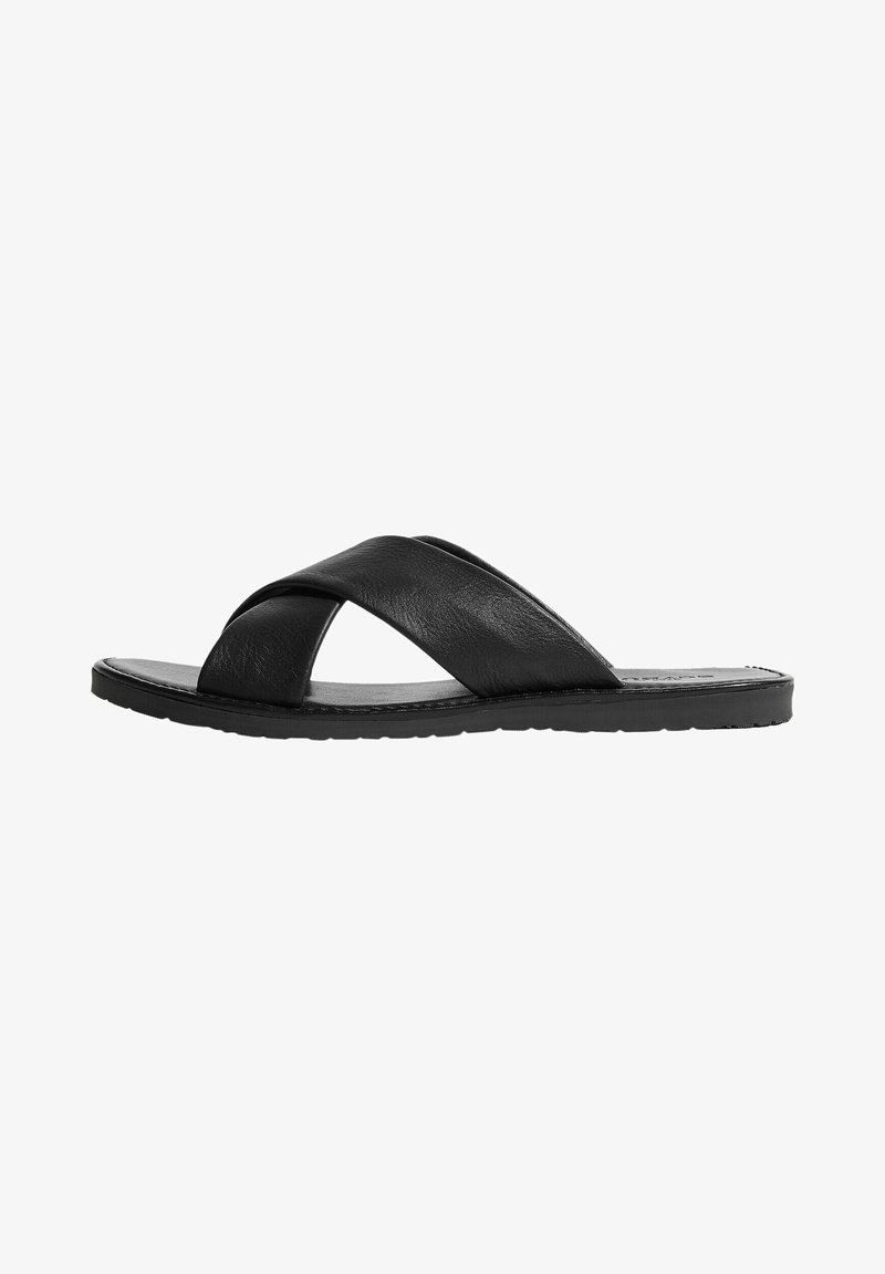 Zwarte leren slidesandalen met een dikke, kruislings gestrapete ontwerp, platte zool en een gladde textuur. Antislip rubberen loopzool.