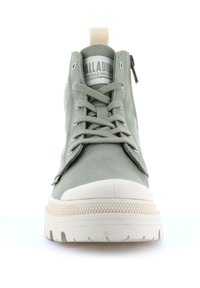 Zapatilla alta de lona gris con punta redonda, suela de goma blanca, diseño de cordones y cremallera lateral. Logo "PALLADIUM" en la lengüeta.
