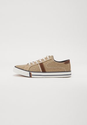 Beige canvas sneakers met bruine leren accenten, een witte rubberen zool en contrasterende streepdetails op de neus. Vlakke veters en een gladde textuur.