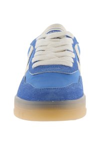 Zapatilla azul y blanca con cordones blancos gruesos, parte superior de ante y tela, suela translúcida de goma, vista desde el frente.