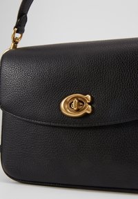 Borsa a tracolla nera in pelle con superficie texturizzata, dotata di una chiusura con design in tonalità oro. Include una tracolla e una chiusura a patta.