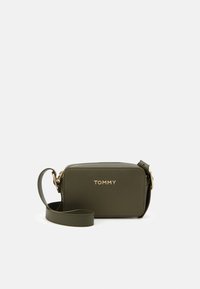 Oliven grøn rektangulær crossbody taske i tekstureret materiale, med et guld logo og en aftagelig rem, sikret med en lynlåslukning.