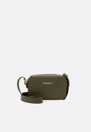 Bolso cruzado rectangular verde oliva en material texturizado, con un logo dorado y una correa desmontable, cerrado con un cierre de cremallera.