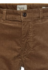 Pantalon en velours côtelé marron avec passants de ceinture, un bouton noir, et une étiquette de la marque "camel active" visible sur la ceinture intérieure.