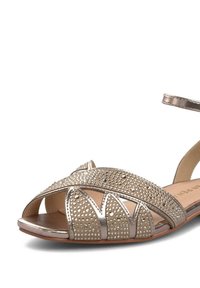 Open-toe sandalen in metallic goud met glinsterende versieringen, voorzien van een enkelbandje en een patroon op de bovenkant. Platte zool met een lichte textuur.