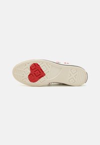 Sko såle i off-white gummi med rødt hjerte design. Har teksturert mønster for grep og buede kanter for stil.