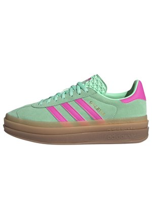 Baskets Adidas en daim vert avec des bandes roses, semelle en gomme multicouche et texte doré "GAZELLE" sur le côté.