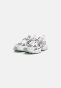 Zapatillas deportivas de malla blanca con detalles en gris, accesorios en rosa y una suela texturizada, que cuentan con un talón acolchado para mayor soporte.