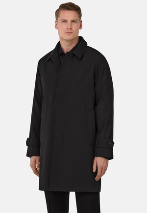 Cappotto trench nero con una texture liscia, dotato di colletto a punta, polsini con bottone e tasche laterali, progettato per una vestibilità su misura.