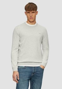 Grauer Sweatshirt mit Rundhalsausschnitt, gerippten Manschetten und Saum. Verfügt über ein kleines Logo auf der Brust und einen weichen, strukturierten Stoff. Getragen mit blauen Jeans.