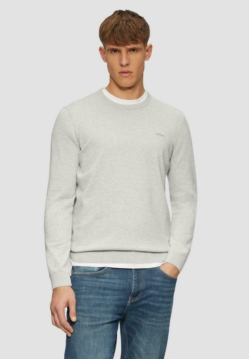 Grauer Sweatshirt mit Rundhalsausschnitt, gerippten Manschetten und Saum. Verfügt über ein kleines Logo auf der Brust und einen weichen, strukturierten Stoff. Getragen mit blauen Jeans.