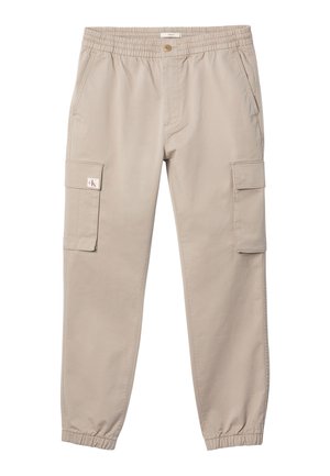 Beežid püksid elastse vöökoha ja mansettidega, nööpidega kinnituv, küljetaskud ja klappidega taskud mõlemal reiel. Vasaku taskuklapi peal väike logo.