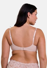 Soutien-gorge beige con spalline regolabili, materiale liscio e chiusura a gancio e occhiello. I dettagli in pizzo sul bordo inferiore aggiungono un tocco decorativo.