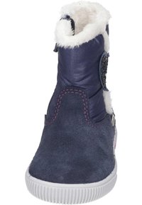 Marineblauwe enkelboot met een suede afwerking, witte nepbont voering, decoratieve patches en een rubberen zool. Voorzien van paarse stikdetails.