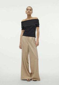 Black off-shoulder top paired with beige wide-leg trousers. Smooth fabric, loose fit, with prominent side seams and a relaxed silhouette.