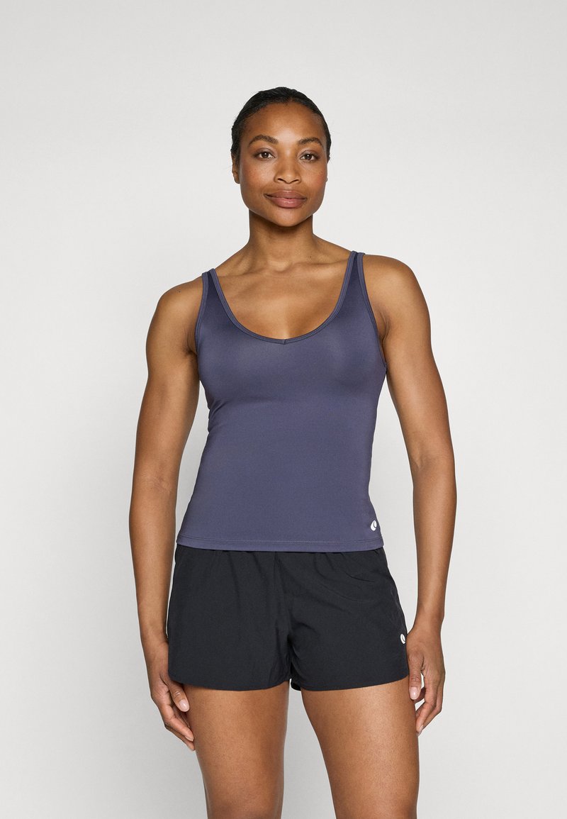 Lilla trenings topp med rund hals og tynne stropper, kombinert med svarte shorts; glatt tekstur og tettsittende design.