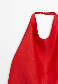 Haut dos nu en lin rouge avec un large décolleté et un dos ouvert. Le tissu présente une finition texturée, offrant une apparence légère et respirante.