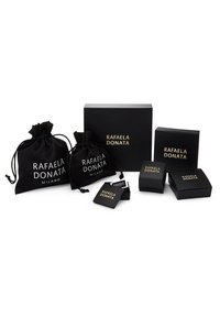 Embalaje negro de Rafaela Donata, que incluye dos bolsitas con cordón y tres cajas, todas con texto dorado en un acabado mate.