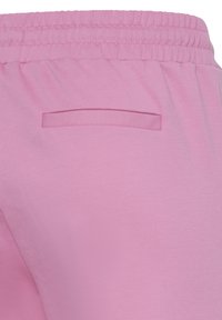 Roosa elastse vöökohaga püksid, millel on üks horisontaalne tagatasku, valmistatud siledast kangast.