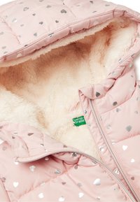 Giacca imbottita rosa con motivi a cuore argentei, con un interno bianco morbido e chiusura con zip. Etichettata "UNITED BENETTON."