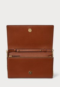 Brūna ādas rokassoma ar zelta pogu. Iekšpuses aprīkojums ietver rāvējslēdzēja kabatu un kartīšu vietas, izklāta ar vieglāku materiālu. Ķēdes siksna.