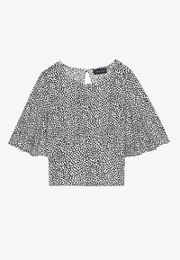 Blůza s krátkým rukávem s černobílým tečkovaným vzorem, s detailem ve tvaru klíčové dírky na zadní straně a rozšířenými rukávy. Měkká látka.