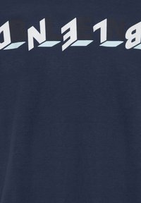 Marineblåt stof med fede hvide bogstaver, der staver "BLEND" i en moderne, geometrisk skrifttype øverst.