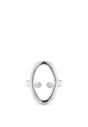 Anillo abierto plateado de forma ovalada con un acabado liso y pulido y una banda ajustable sobre un fondo blanco.