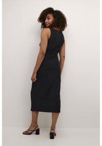 Black sleeveless dress made of soft fabric, featuring a mid-length design with subtle ruching detail along the back and a straight hem.